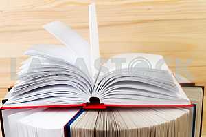 Открытая книга, стопка книг в твердом переплете на деревянном столе. Обратно в школу. Копирование пространства