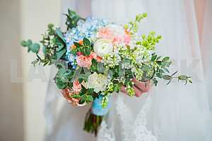 Bride holding a beautiful wedding bouquet of white and blue, rosy flowers, spring