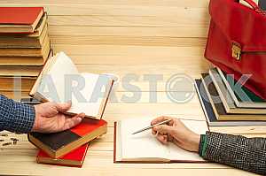 On a wooden table books, documents, calculator, red briefcase.