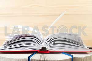 Открытая книга, стопка книг в твердом переплете на деревянном столе. Обратно в школу. Копирование пространства