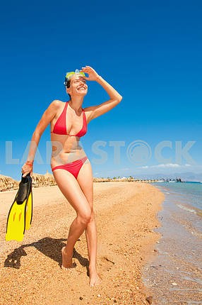 girl in a red bikini with a mask and flippers on the beach