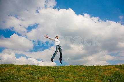 Happy young man - jumping  against backdrop of blue sky.