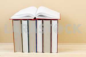 Открытая книга, стопка книг в твердом переплете на деревянном столе. Обратно в школу. Копирование пространства