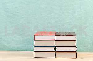 Открытая книга, стопка книг в твердом переплете на деревянном столе. Обратно в школу. Копирование пространства
