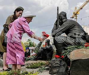 Old woman lays flowers at the monument to fallen soldiers in May 2012