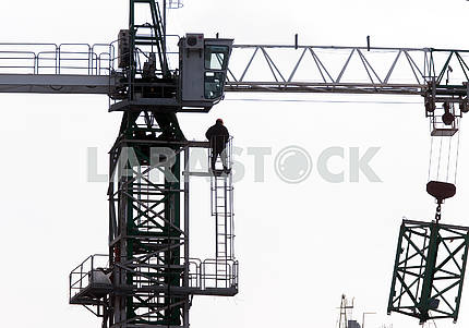 Silhouettes of cranes with a load on the construction of buildin