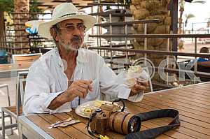 A man in a hat with a camera in a cafe