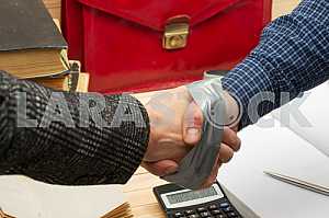 On a wooden table books, documents, calculator, red briefcase.