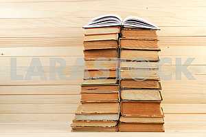 Открытая книга, стопка книг в твердом переплете на деревянном столе. Обратно в школу. Копирование пространства