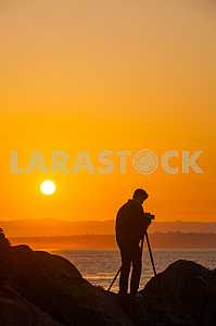 Photographer is standing on the Pacific coast at sunrise