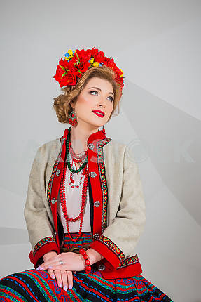 a beautiful girl in National Ukrainian Costume. captured in studio. Embroidery and jacket. wreath. circlet of flowers. red lips