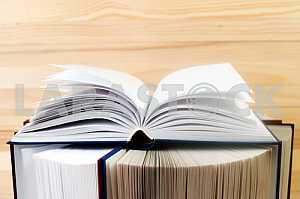 Open book, stack of hardback books on wooden table. Back to school. Copy space