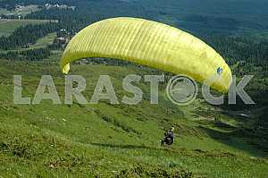 Paraglider flying over mountains on a summer day
