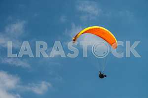 Paraglider flying over mountains on a summer day