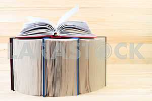 Открытая книга, стопка книг в твердом переплете на деревянном столе. Обратно в школу. Копирование пространства