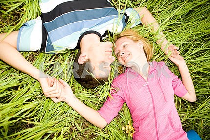 Young love couple lay on green grass outdoors