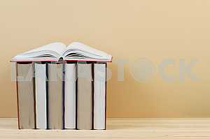 Открытая книга, стопка книг в твердом переплете на деревянном столе. Обратно в школу. Копирование пространства