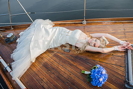 happy honeymoon sailing - Stylish young beautiful bride laying on the wooden board the sailing yacht - happyly lookin