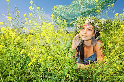 Happy young beautiful girl lying in flowers