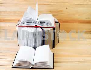 Открытая книга, стопка книг в твердом переплете на деревянном столе. Обратно в школу. Копирование пространства