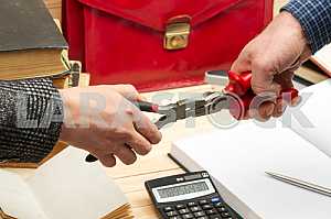 On a wooden table books, documents, calculator, red briefcase.