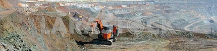 Panorama of the iron ore quarry with an excavator