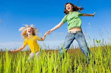 Happy woman and girl making exercises on field.