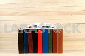 Open book, stack of hardback books on wooden table. Back to school. Copy space