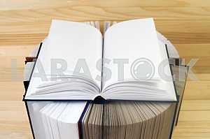Открытая книга, стопка книг в твердом переплете на деревянном столе. Обратно в школу. Копирование пространства