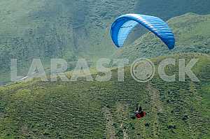 Paraglider flying over mountains on a summer day