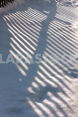 fence shadow on snow accumulated deck