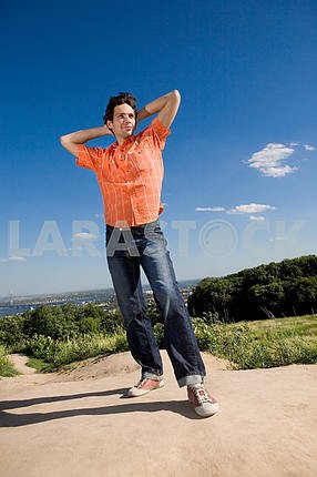 Young man winning on peak of a mountain. Against a blue sky with
