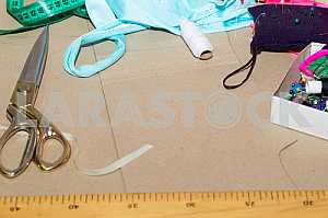 Scissors, reel of thread, measuring tapes and natural fabric. Sewing textile or cloth. Work table of a tailor. Textile tools. Copy space. Top view