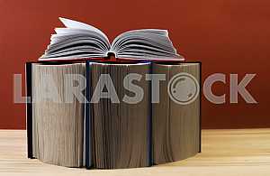 Открытая книга, стопка книг в твердом переплете на деревянном столе. Обратно в школу. Копирование пространства