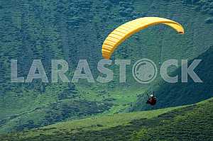 Paraglider flying over mountains on a summer day