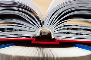 Открытая книга, стопка книг в твердом переплете на деревянном столе. Обратно в школу. Копирование пространства