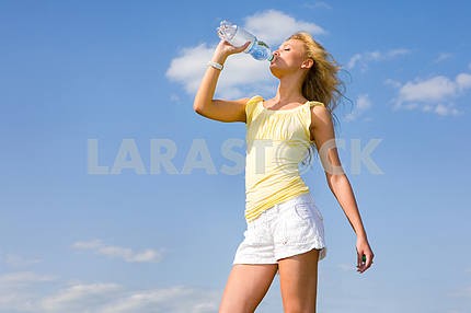Beautiful girl drinking water against blue sky