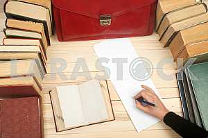 On a wooden table books, documents, calculator, red briefcase.