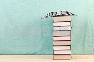 Открытая книга, стопка книг в твердом переплете на деревянном столе. Обратно в школу. Копирование пространства