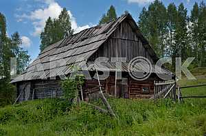 Lonely old wood house on a mountain hill against cloudy sky.