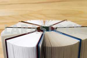 Открытая книга, стопка книг в твердом переплете на деревянном столе. Обратно в школу. Копирование пространства