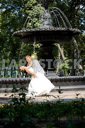 Groom and bride joy against backdrop fountain