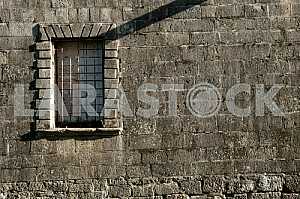 Старая каменная стена с окном и решеткой