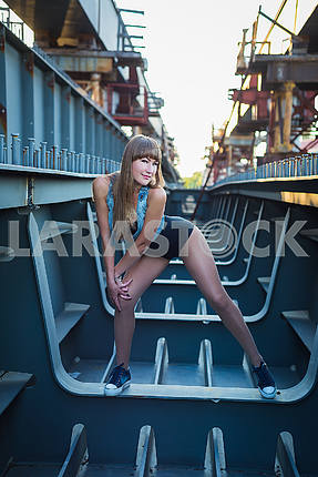 A light hair girl posing on the unfinished bridge showing her legs and smiling.  a hot lady on a sunny day
