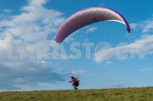 Paraglider flying over mountains on a summer day