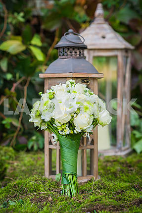 the wedding bouquet for the bride made of white roses and green chrysanthemum  Vintage wooden lantern and moss on the background