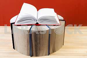 Открытая книга, стопка книг в твердом переплете на деревянном столе. Обратно в школу. Копирование пространства