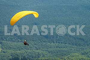 Paraglider flying over mountains on a summer day