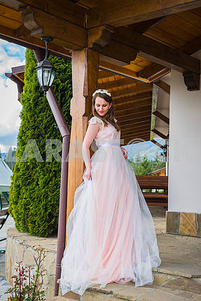 Beautiful bride in long dress stands at the door and looks outside. Tulle Dress  Lovely girl