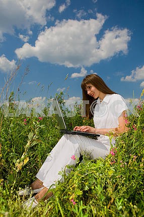 Young woman on the grass field with a laptop